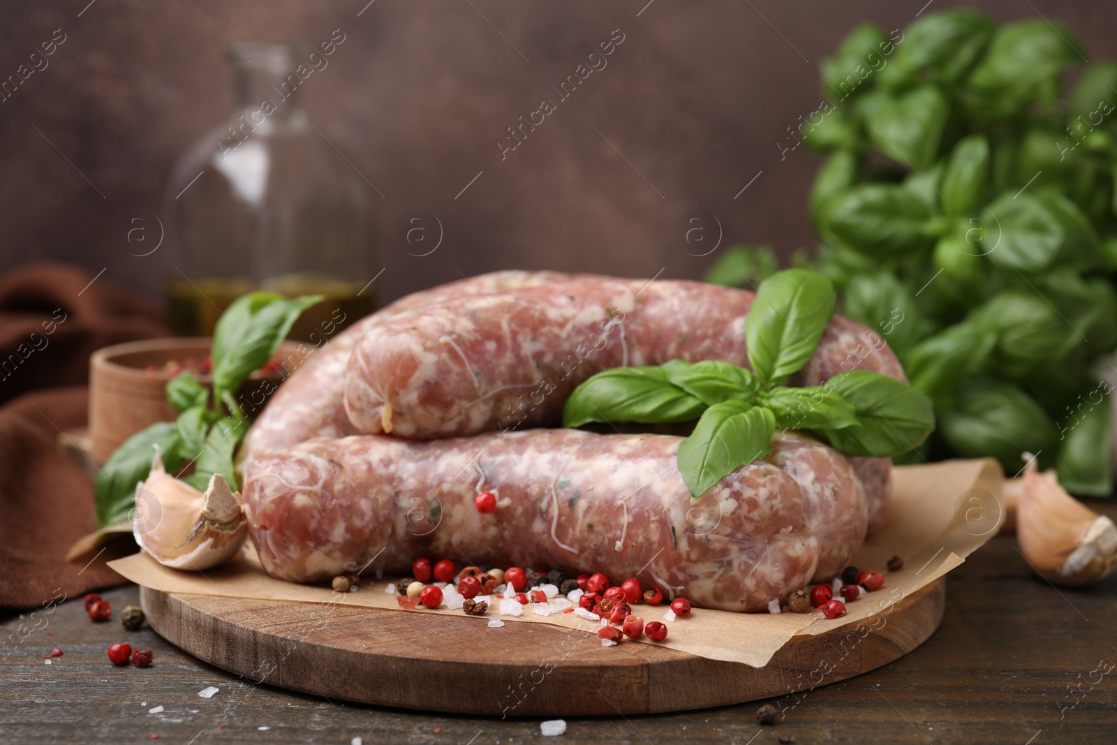 Photo of Raw homemade sausages and different spices on wooden table