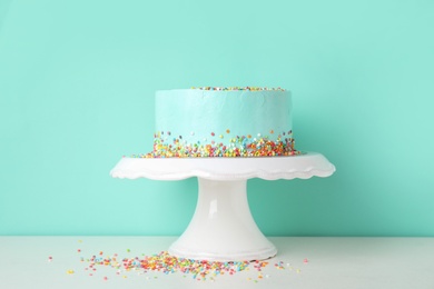 Photo of Fresh delicious birthday cake on stand against color background