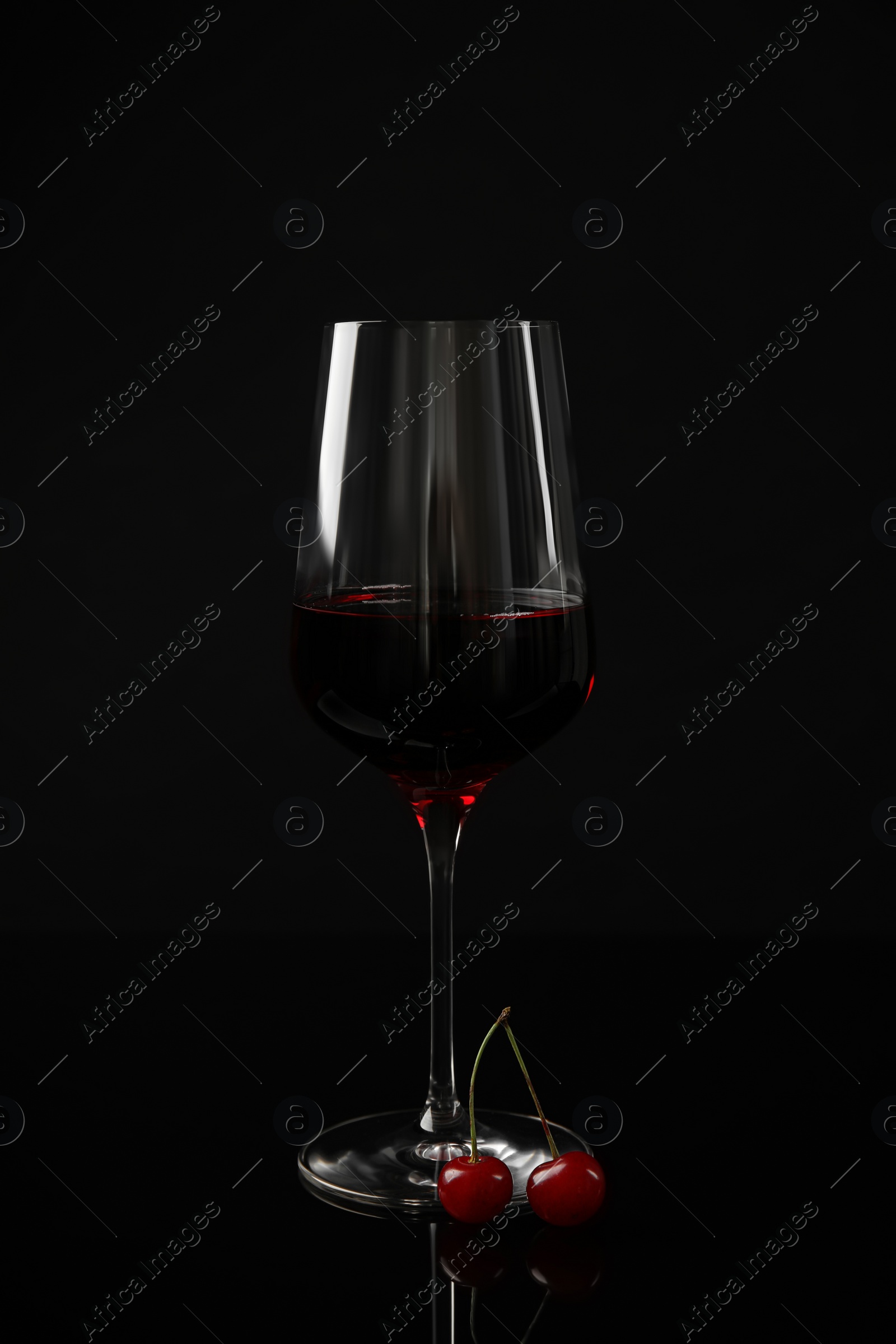 Photo of Delicious cherry wine with ripe juicy berries on black background