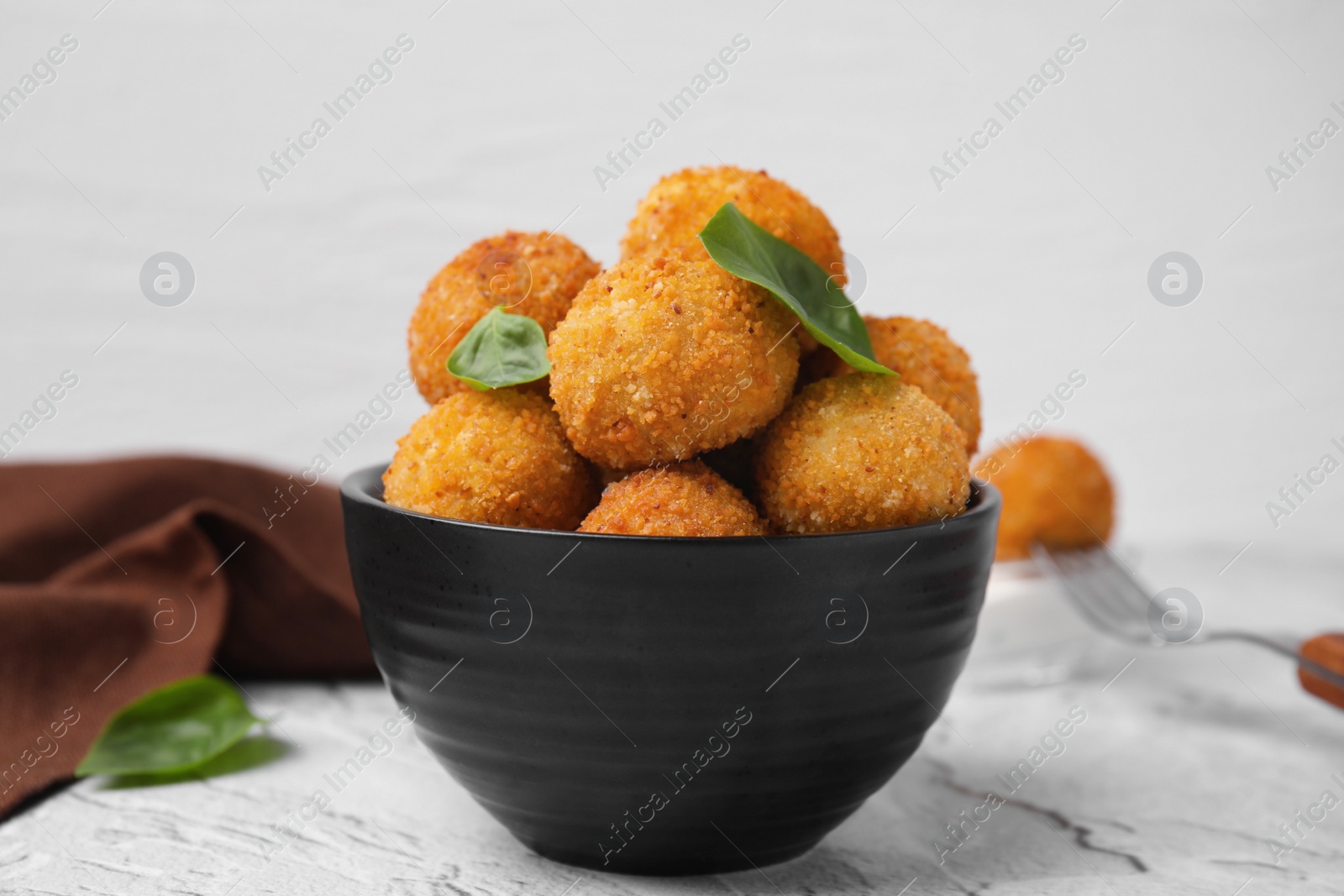 Photo of Bowl of delicious fried tofu balls with basil on textured table