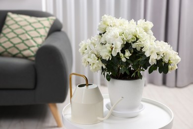 Photo of Beautiful azalea plant in flower pot and watering can on white table in room, space for text