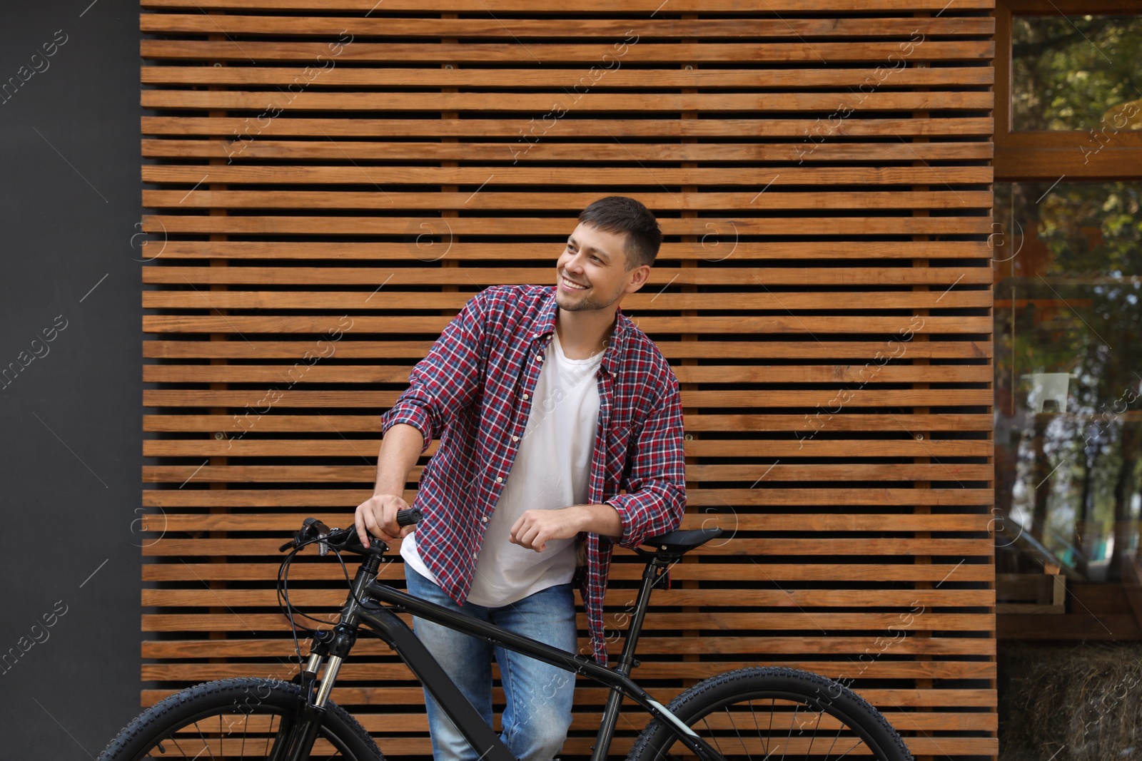 Photo of Handsome man with modern bicycle near building outdoors