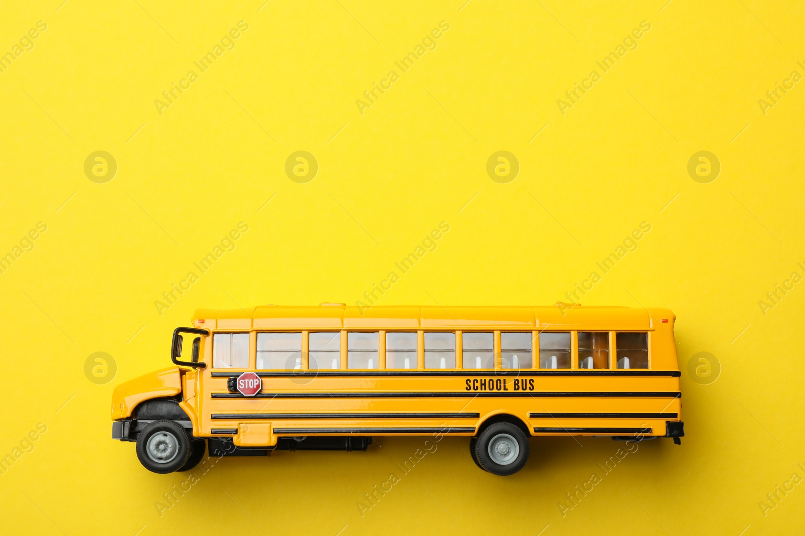 Photo of School bus on yellow background, top view with space for text. Transport service