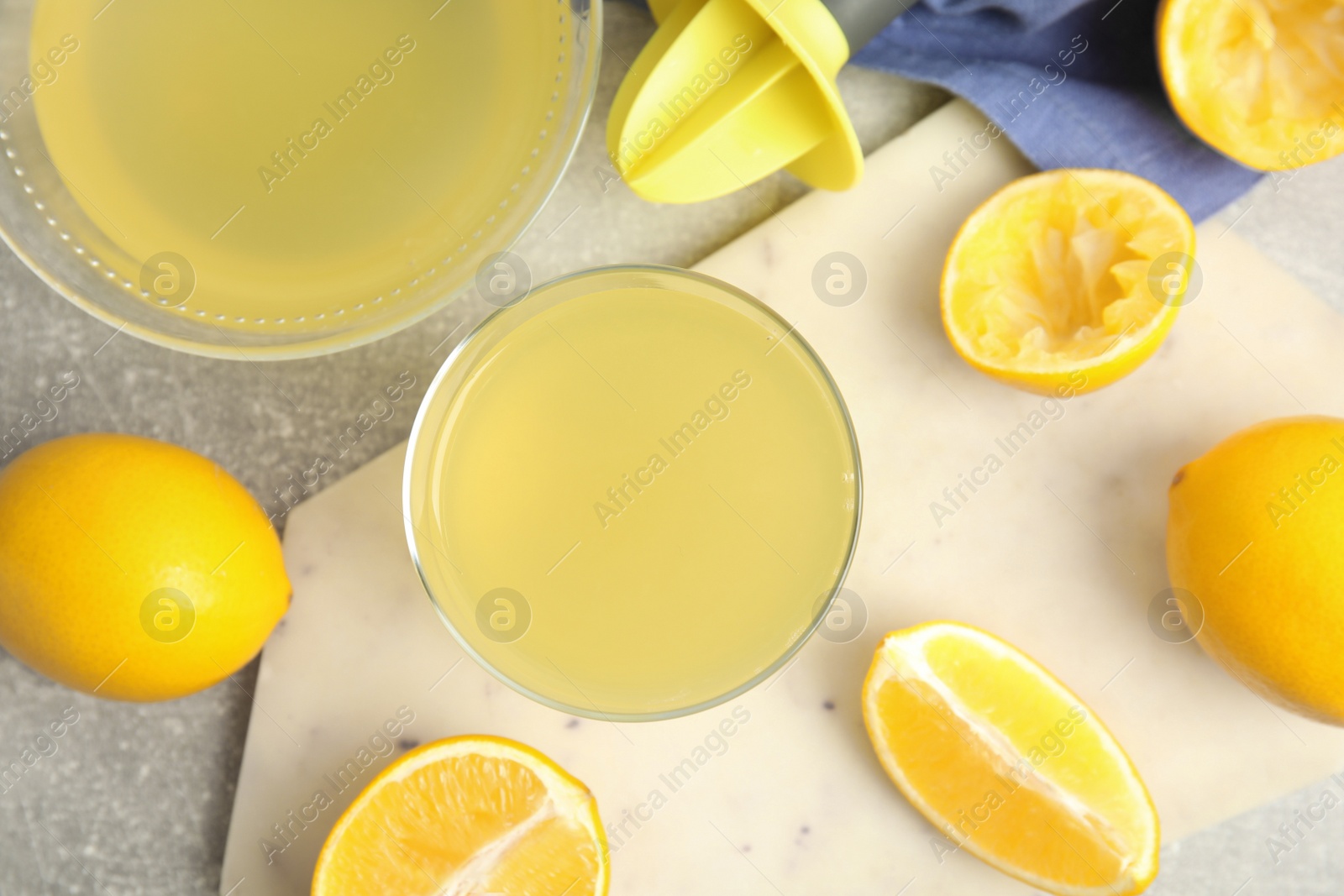 Photo of Freshly squeezed lemon juice on grey table, flat lay
