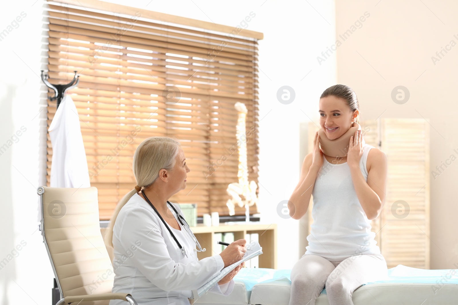 Photo of Female orthopedist examining patient with injured neck in clinic