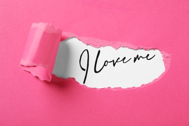 Photo of Handwritten phrase I Love Me through torn pink paper on white background, top view