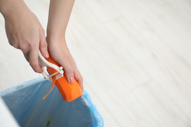 Photo of Woman peeling fresh carrot above garbage bin, closeup. Space for text