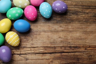 Photo of Colorful eggs on wooden background, flat lay with space for text. Happy Easter