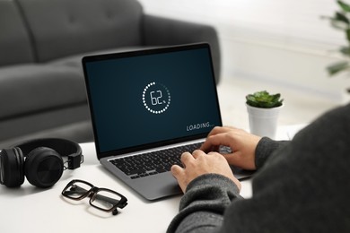 Image of Loading screen displaying progress. Man working on laptop at table indoors, closeup