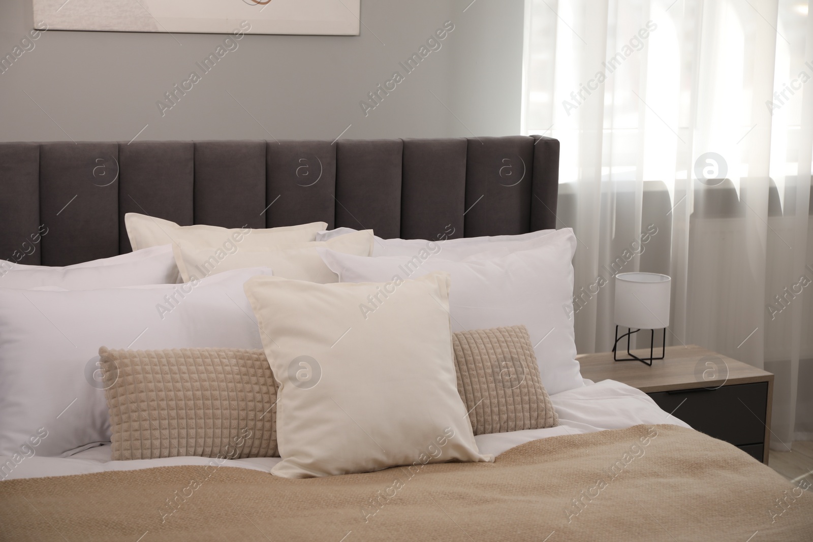 Photo of Many soft white pillows and blanket on bed indoors