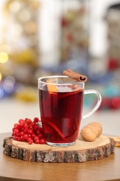 Photo of Aromatic mulled wine in glass cup on wooden table against blurred background
