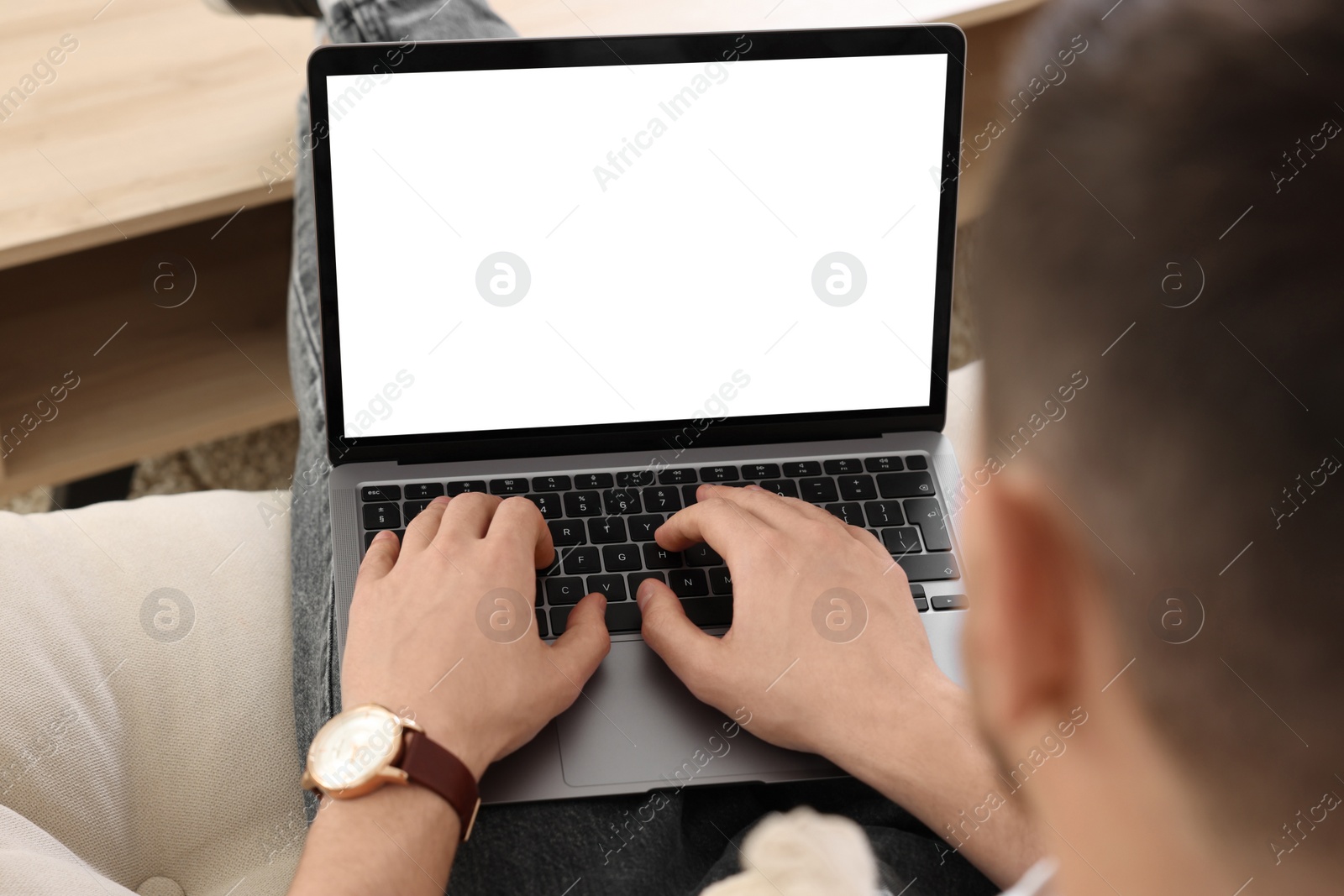 Photo of Man working with laptop on sofa indoors, closeup