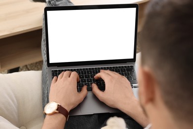 Man working with laptop on sofa indoors, closeup