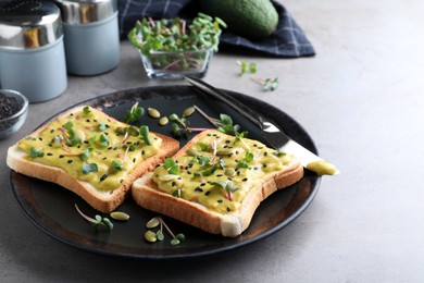 Photo of Delicious sandwiches with guacamole, seeds and microgreens on grey table
