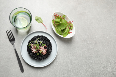 Photo of Delicious black risotto with seafood served on light grey table. Space for text