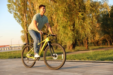 Photo of Handsome young man riding bicycle on city waterfront