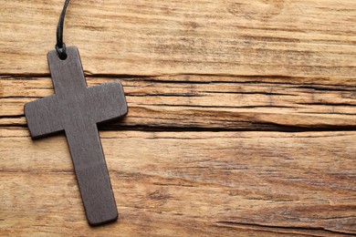 Photo of Wooden Christian cross on table, top view. Space for text