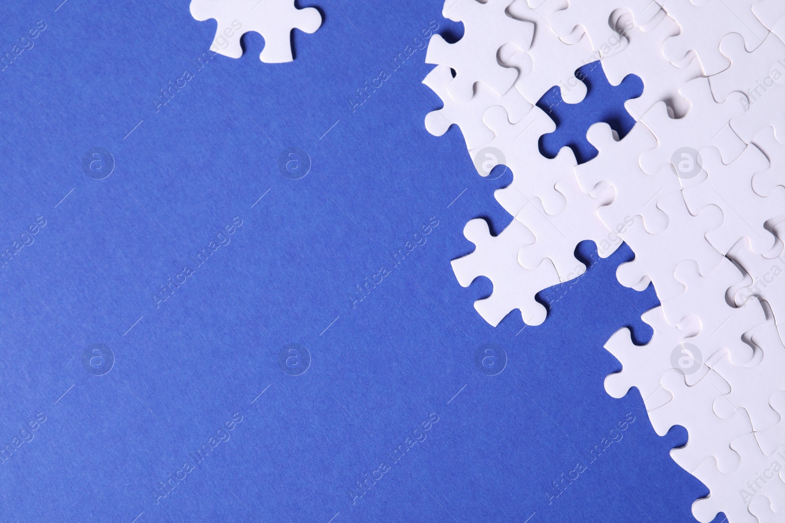 Photo of Blank white puzzle pieces on blue background, flat lay. Space for text