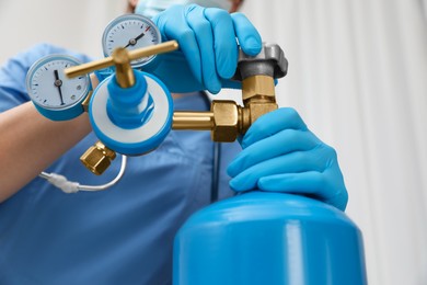 Photo of Medical worker checking oxygen tank in hospital room, closeup