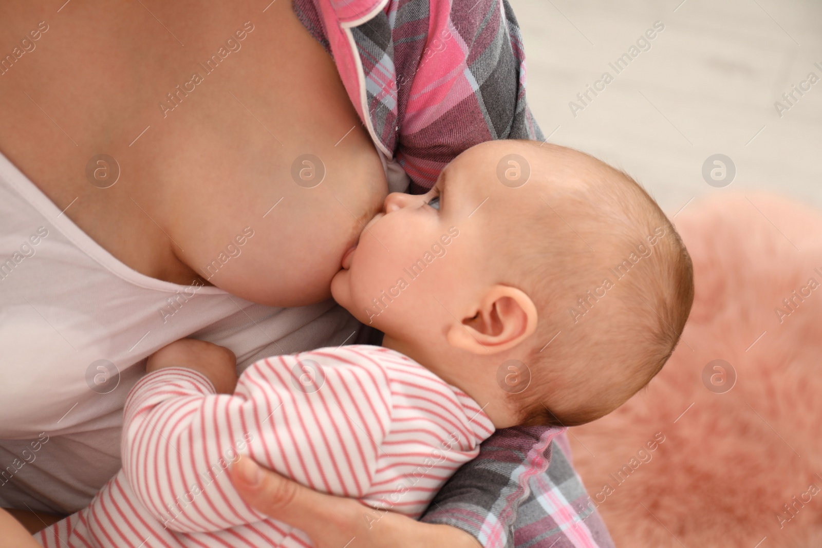 Photo of Young woman breastfeeding her little baby at home, closeup