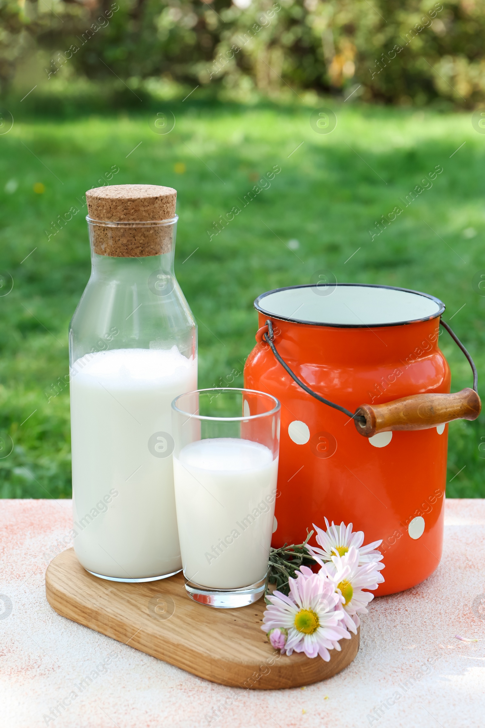 Photo of Tasty fresh milk on color textured table outdoors