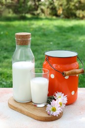 Photo of Tasty fresh milk on color textured table outdoors