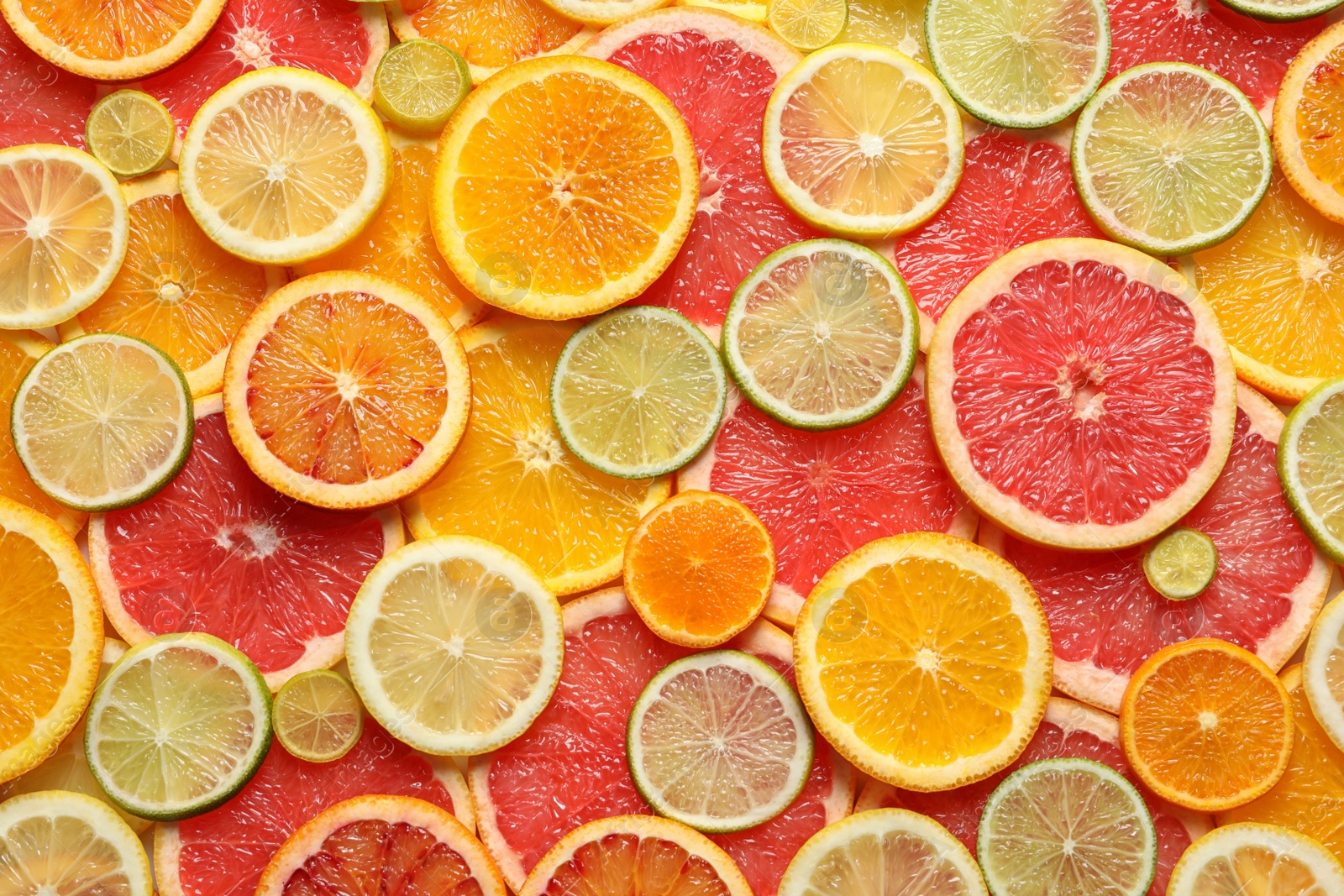 Photo of Slices of fresh citrus fruits as background, top view