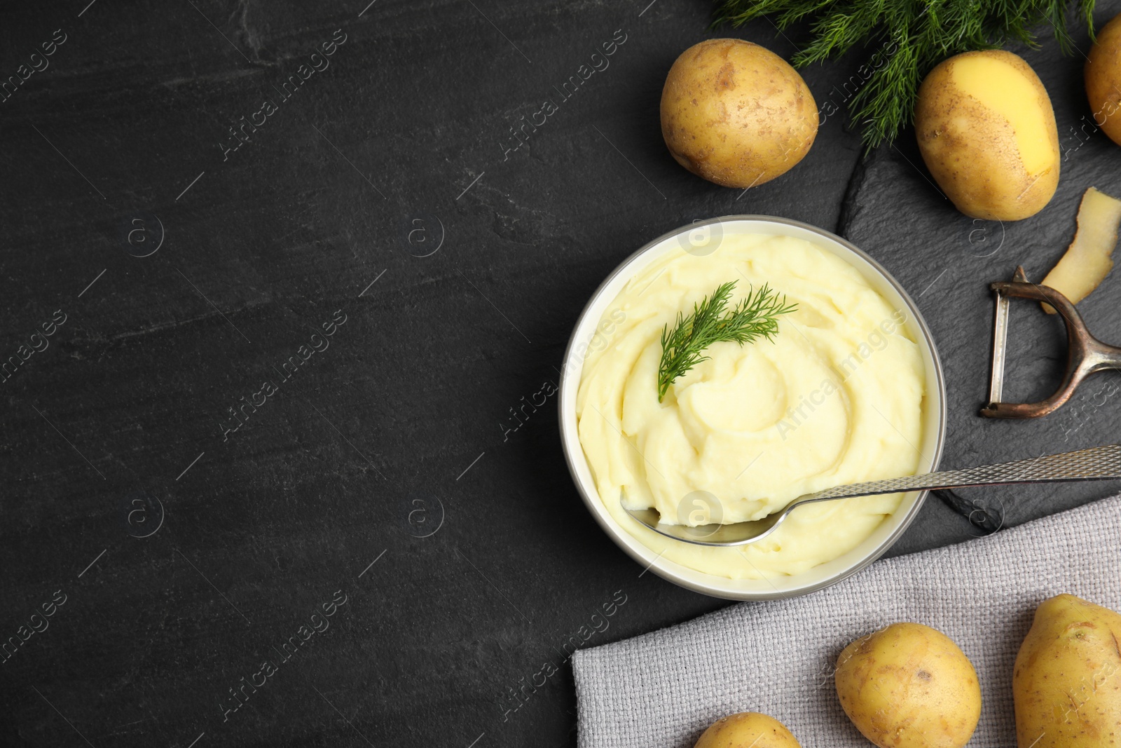 Photo of Freshly cooked homemade mashed potatoes and raw vegetables on black table, flat lay. Space for text