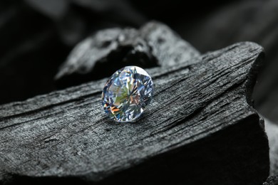 Photo of Beautiful shiny diamond on coal, closeup view