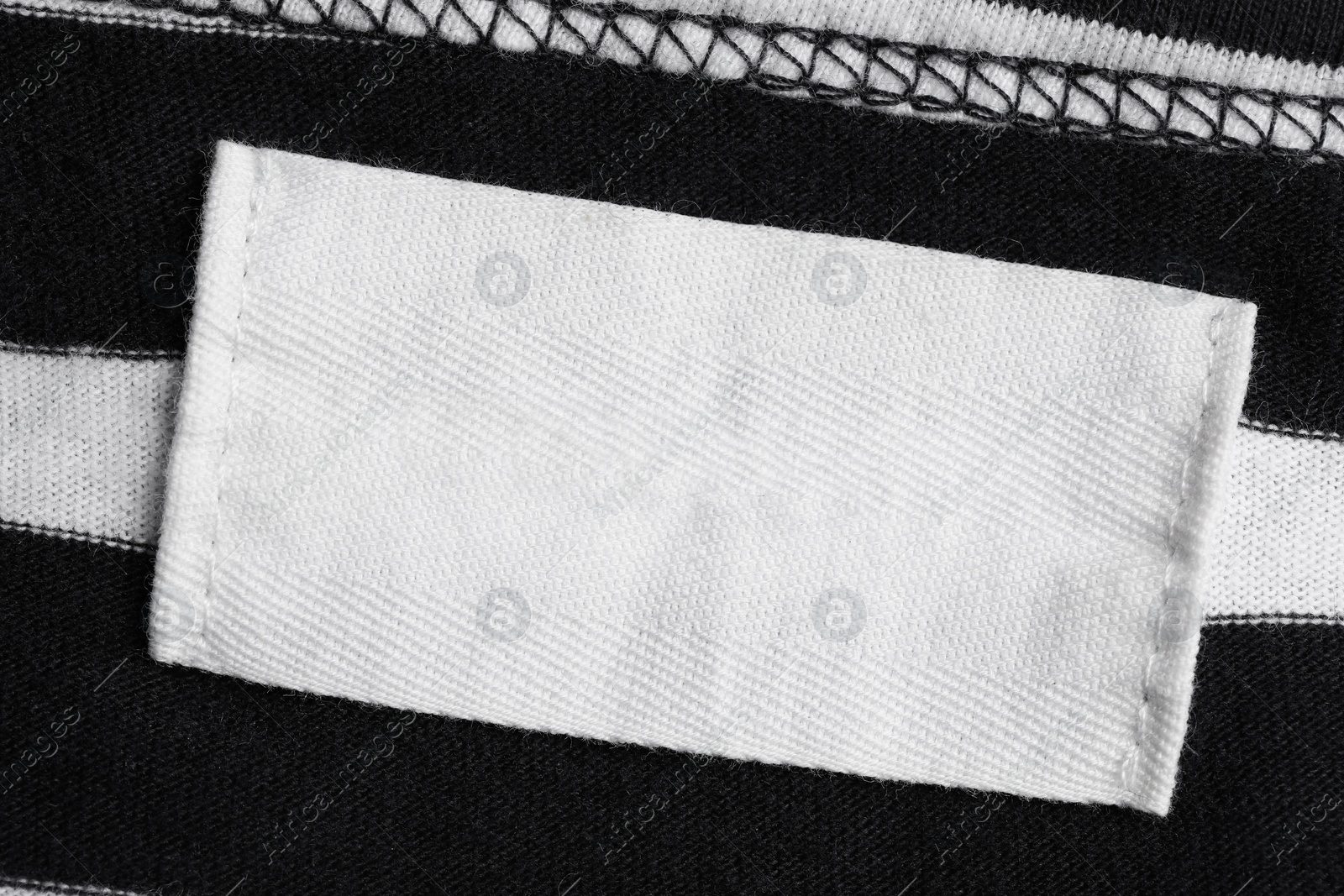 Photo of Empty clothing label on striped garment, top view