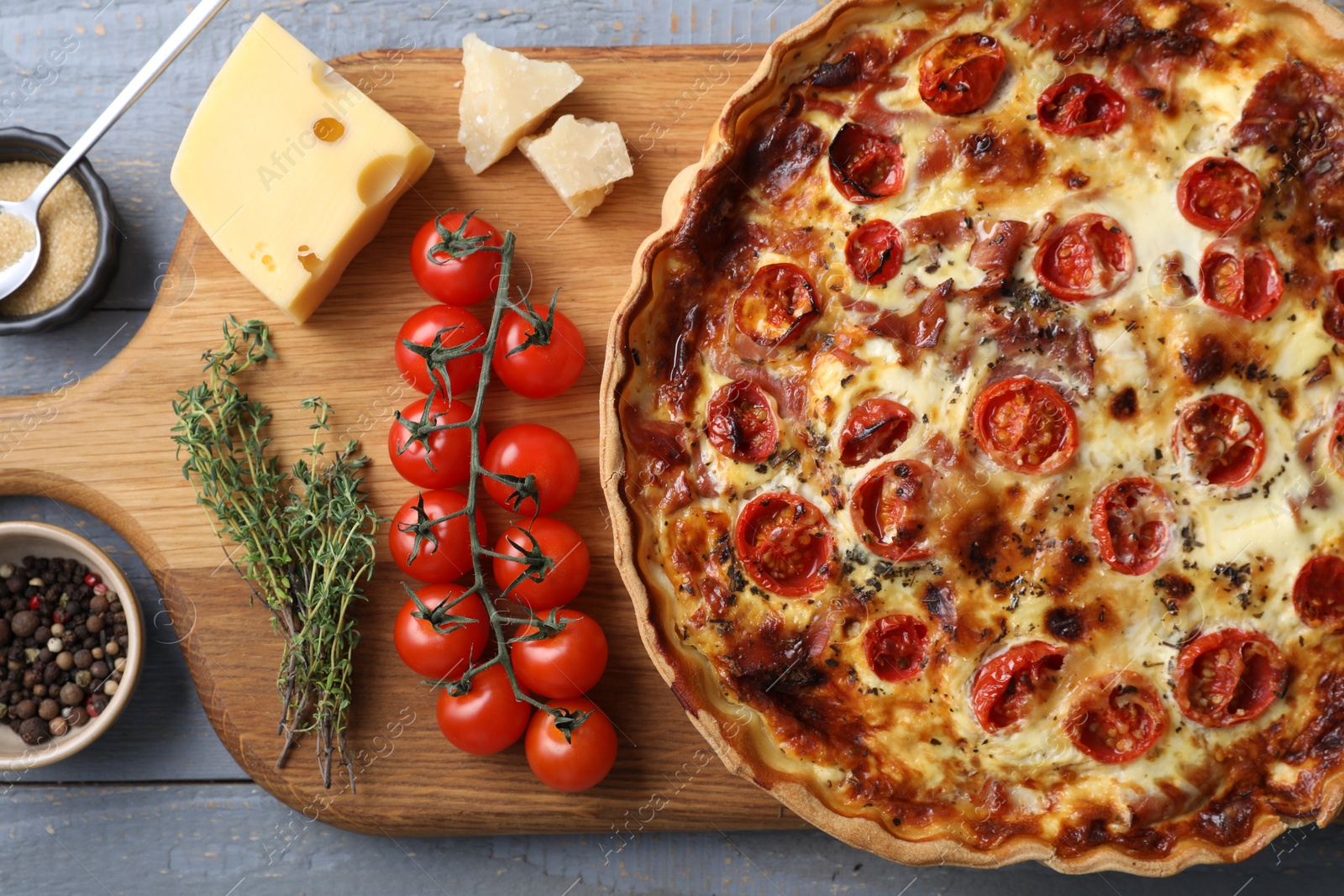 Photo of Delicious homemade prosciutto quiche and ingredients on table, flat lay