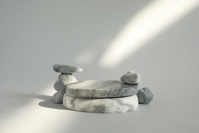 Photo of Presentation for product. Stone podium and pebbles on light grey background. Space for text