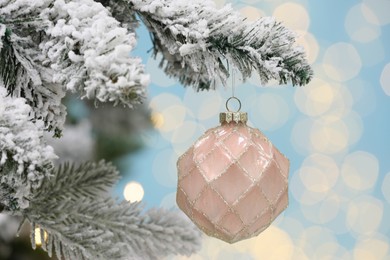 Beautiful bauble hanging on Christmas tree against blurred festive lights, closeup