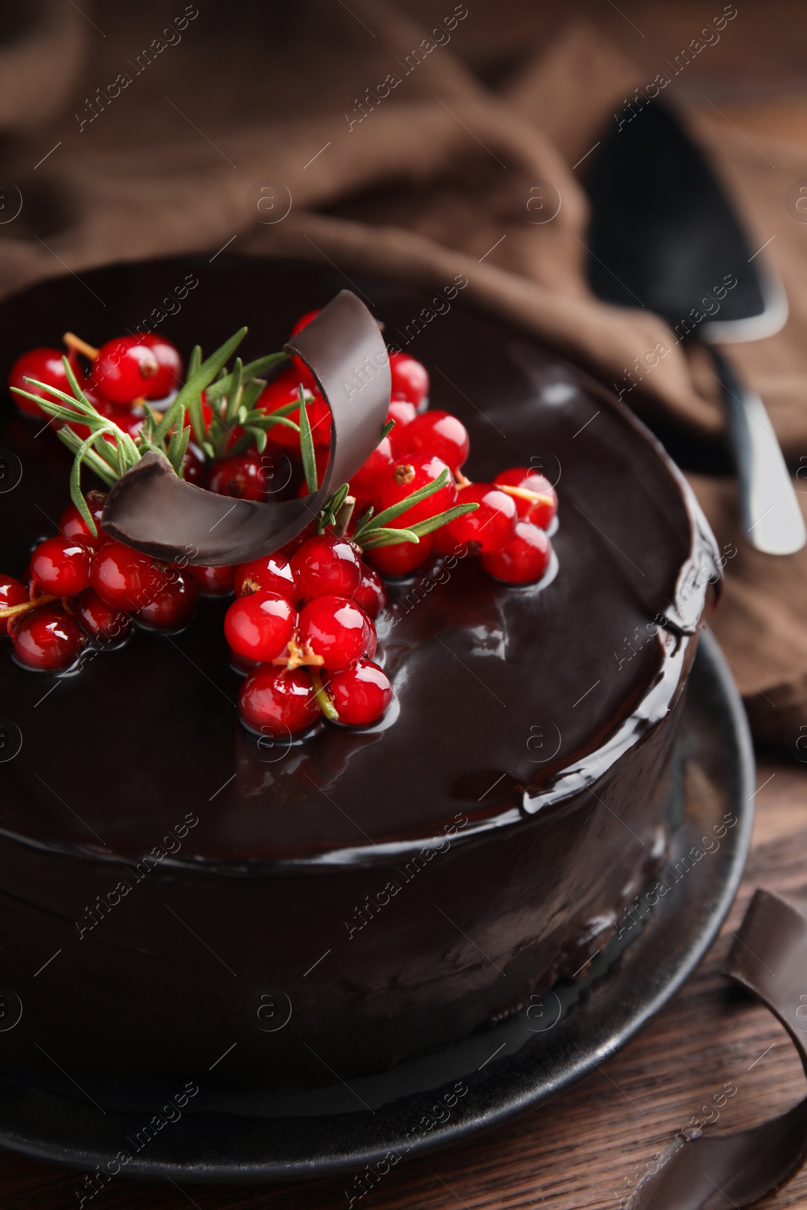 Photo of Tasty homemade chocolate cake with berries and rosemary on wooden table, closeup