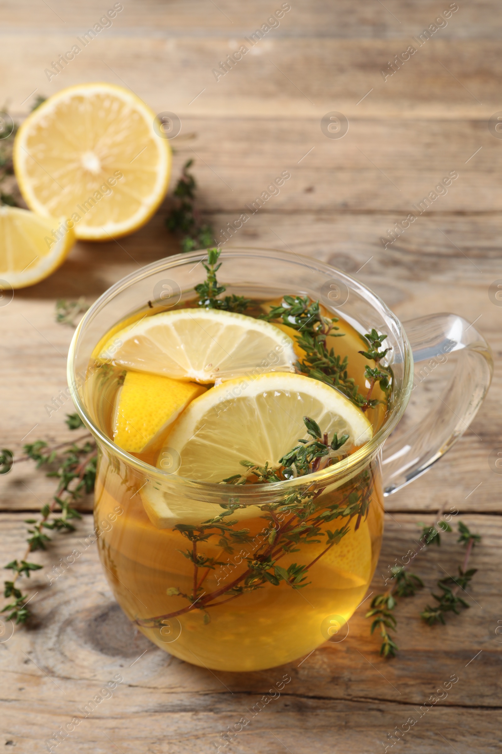 Photo of Aromatic herbal tea with thyme and lemon on wooden table