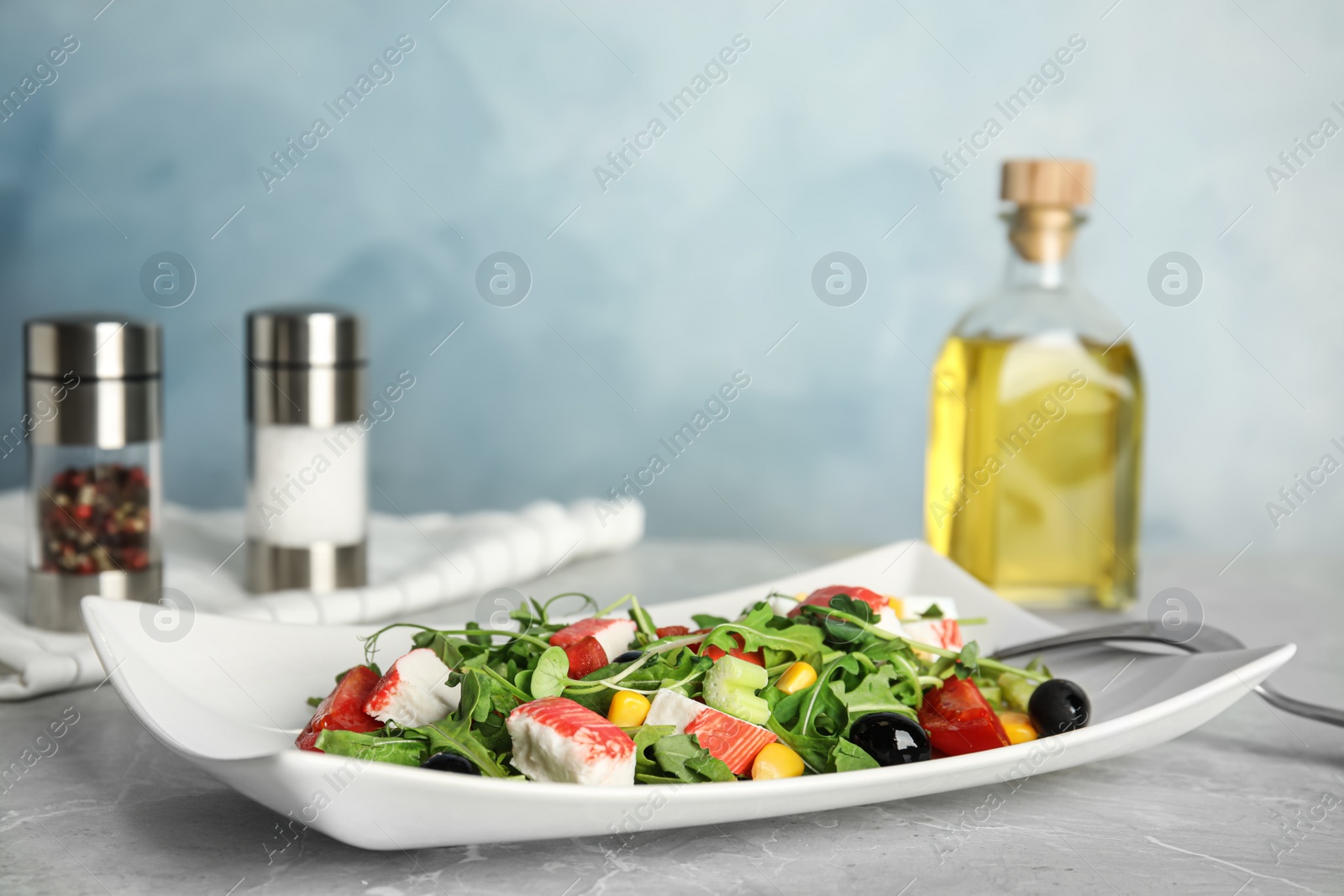 Photo of Tasty crab stick salad served on grey marble table, space for text