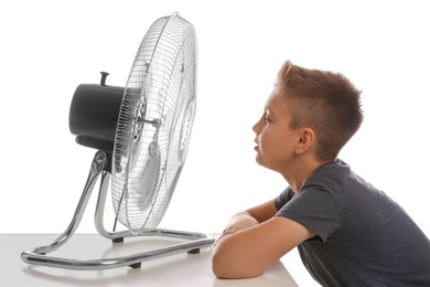 Photo of Little boy enjoying air flow from fan on white background. Summer heat