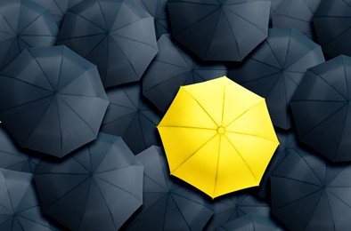 Image of Yellow umbrella standing out of other ones, top view