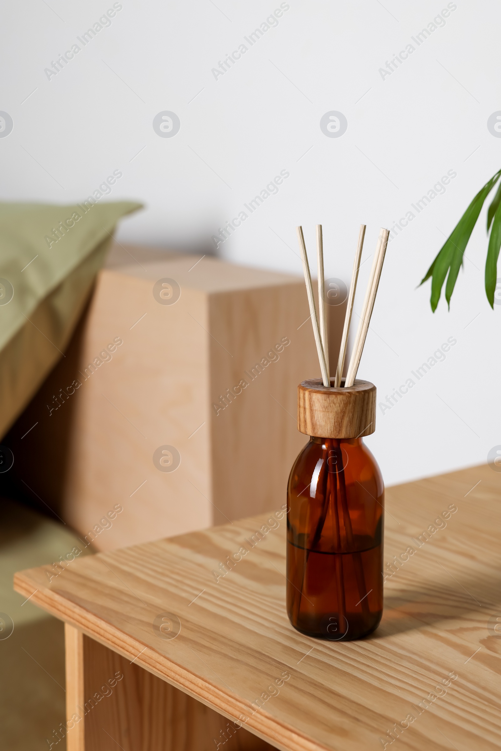 Photo of Aromatic reed air freshener on wooden table indoors. Space for text