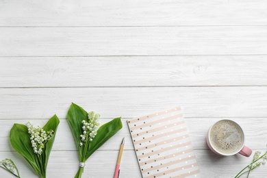 Flat lay composition with notebook, lily of the valley bouquets and coffee on white wooden background. Space for text