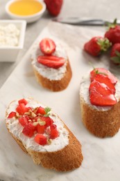 Photo of Delicious ricotta bruschettas with strawberry and mint on plate, closeup