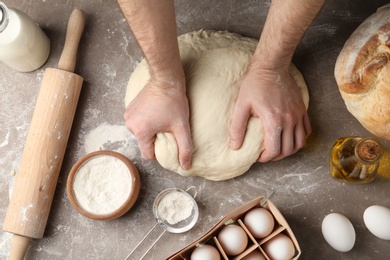 Male baker preparing bread dough at kitchen table, top view
