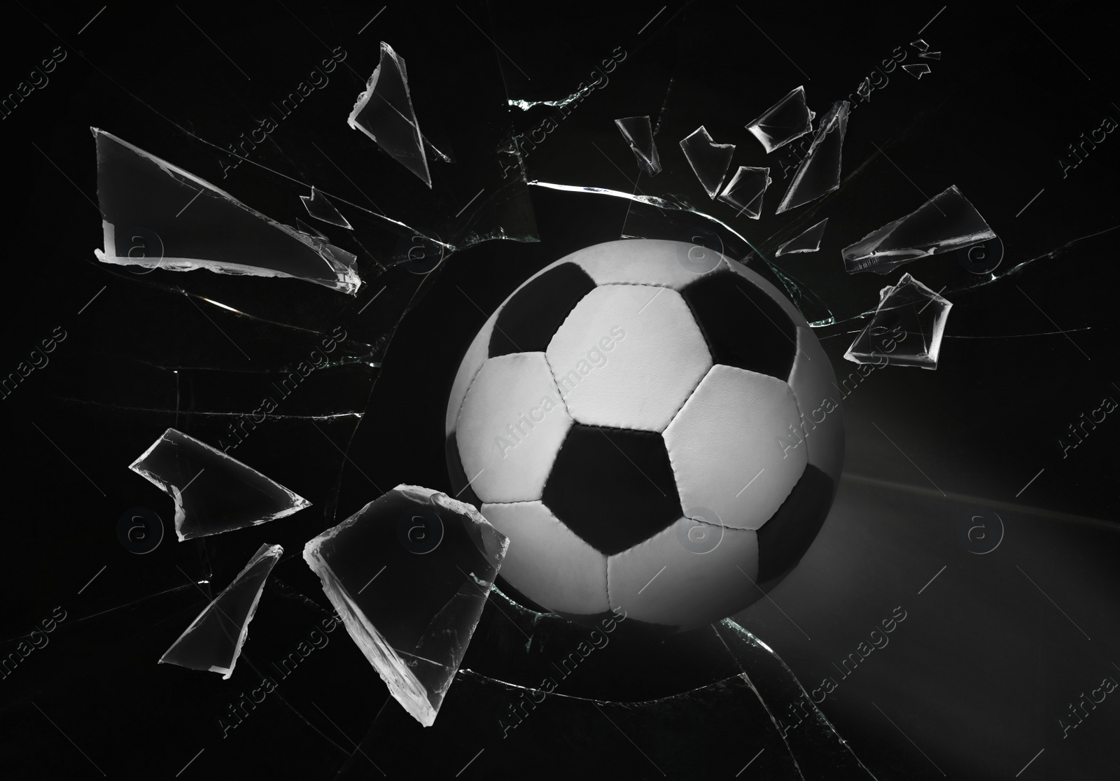 Image of Soccer ball breaking up glass against black background