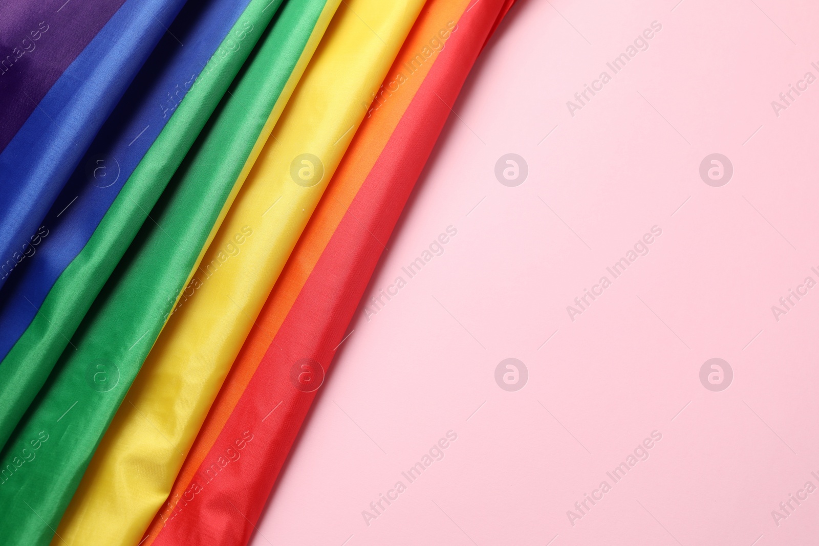 Photo of Rainbow LGBT flag on pink background, top view. Space for text