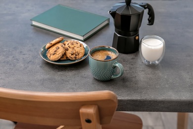 Cup of aromatic hot coffee and cookies on table