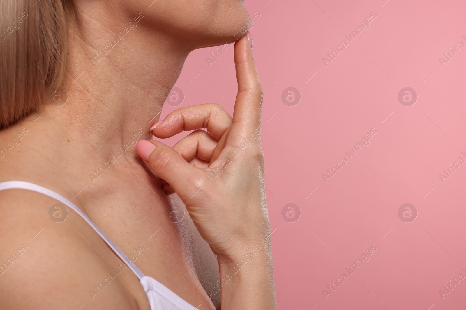 Photo of Woman touching her neck on pink background, closeup. Space for text