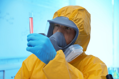 Scientist in chemical protective suit with test tube at laboratory. Virus research