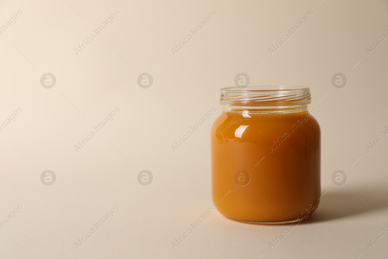 Photo of Jar with healthy baby food on beige background. Space for text