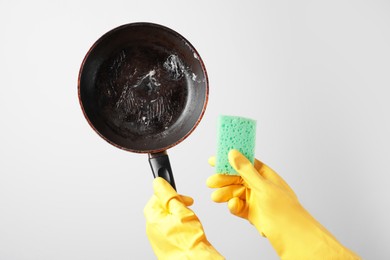 Photo of Woman holding dirty frying pan and sponge on white background, closeup