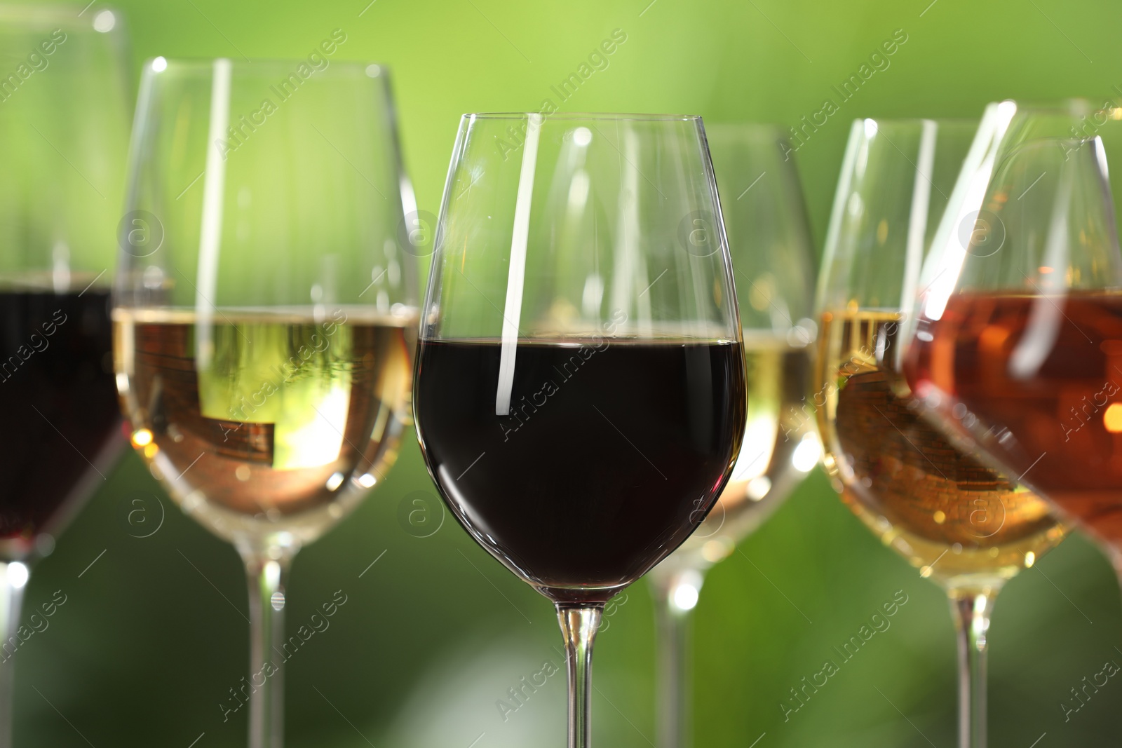 Photo of Different tasty wines in glasses against blurred background